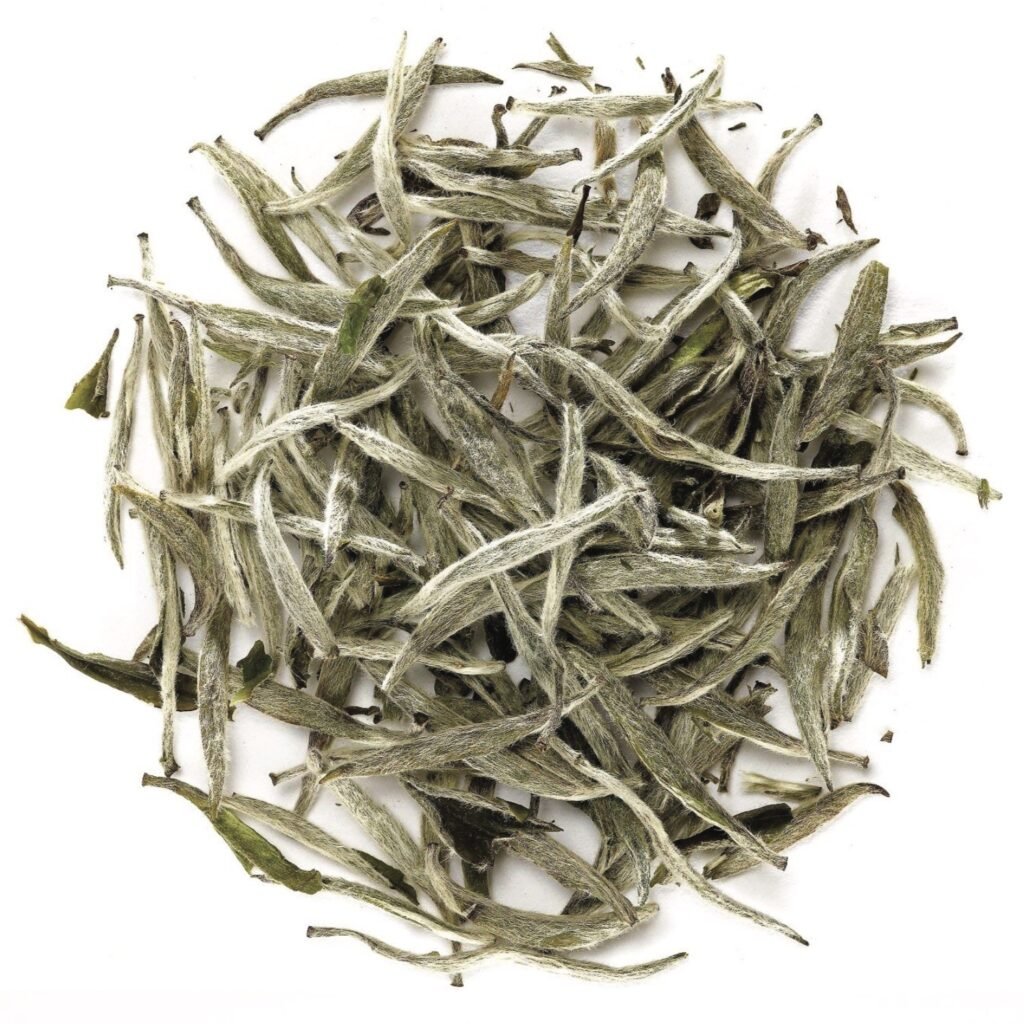 Loose silver needle white tea leaves, close-up view, showcasing fine texture and natural color.