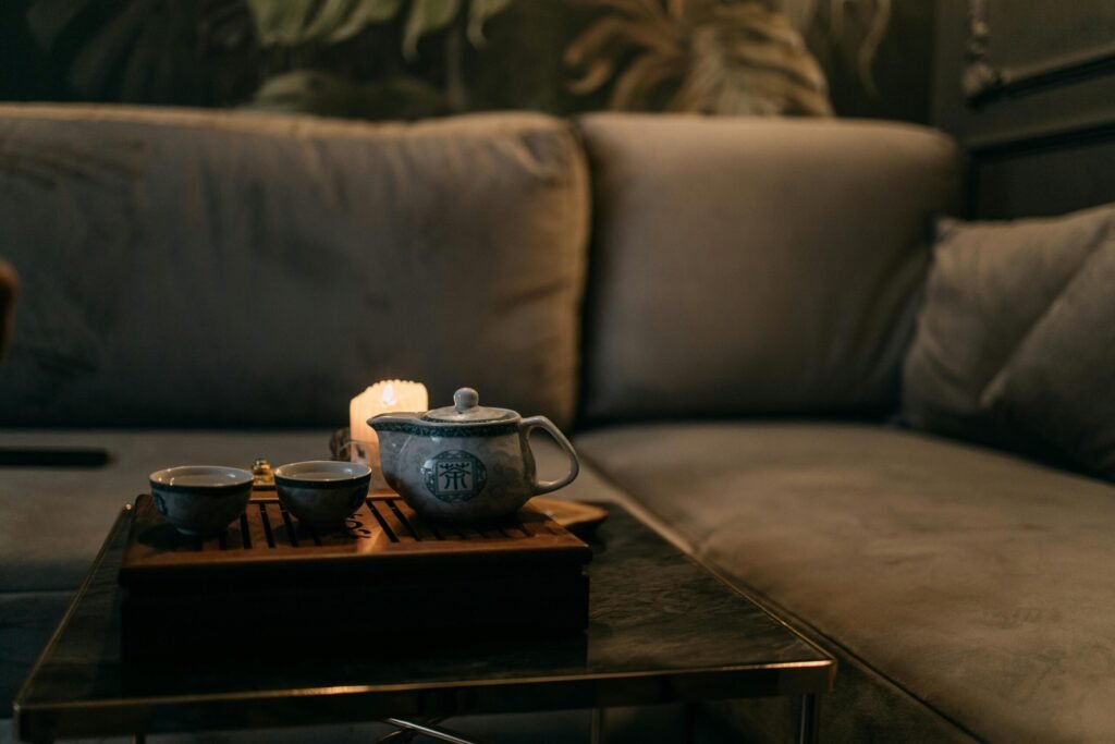 Cozy living room with candlelit tea set on table, inviting ambiance.