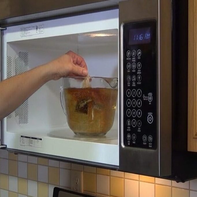 Person heating food in a microwave in a modern kitchen.