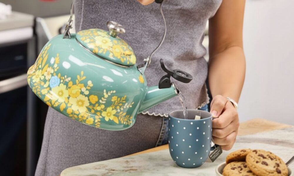 How to Brew Tea with a Kettle: A Simple Guide for Perfectly Brewed Tea Person pouring hot water from a floral kettle into a polka dot mug beside cookies.