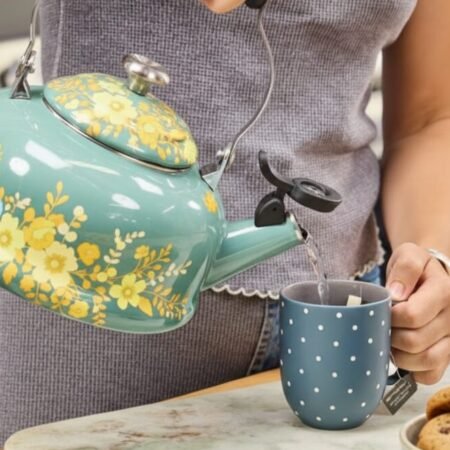 How to Brew Tea with a Kettle: A Simple Guide for Perfectly Brewed Tea Person pouring hot water from a floral kettle into a polka dot mug beside cookies.