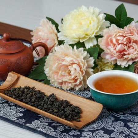 Brewing Oolong Tea: A Guide to Steeping the Finest Oolong Leaves from Taiwan Tea setup with a teapot, cup, and floral decor on a patterned tablecloth for a relaxing atmosphere.