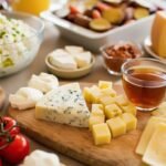 A diverse cheese platter with fruits, nuts, and tea, ideal for a gourmet breakfast or brunch setting.