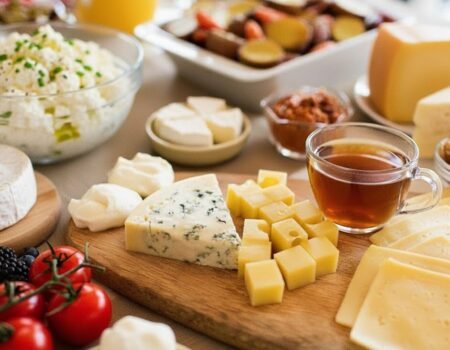A diverse cheese platter with fruits, nuts, and tea, ideal for a gourmet breakfast or brunch setting.