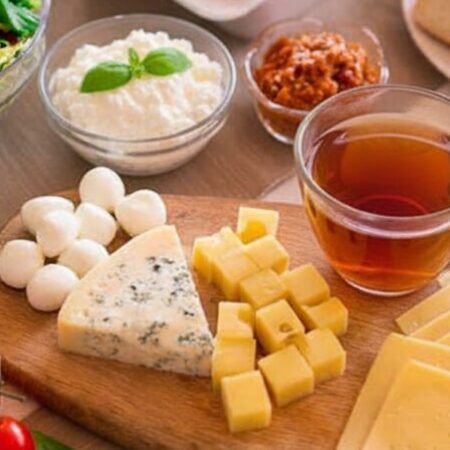 Cheese and salad brunch with tea, fresh fruits, and bread on a table setting, offering a variety of healthy options.
