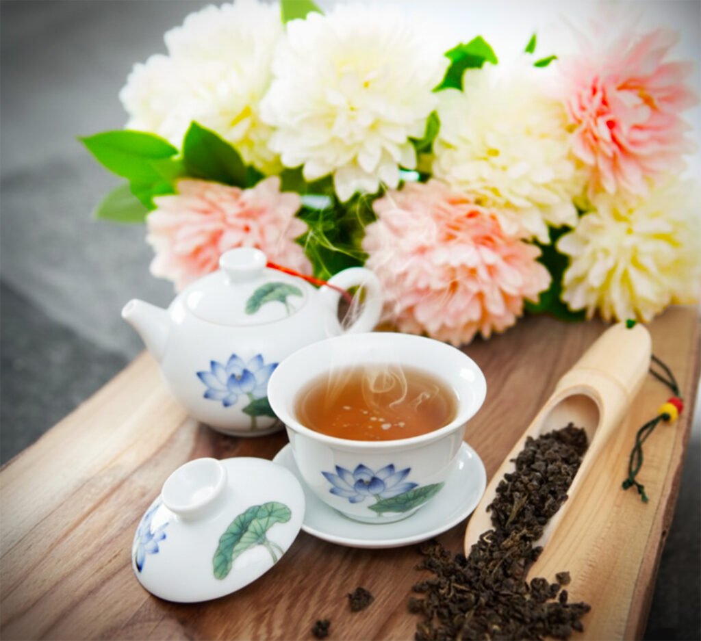 Steaming tea in floral china with flowers and loose leaf tea on a wooden tray. Perfect for a tranquil tea time setting.